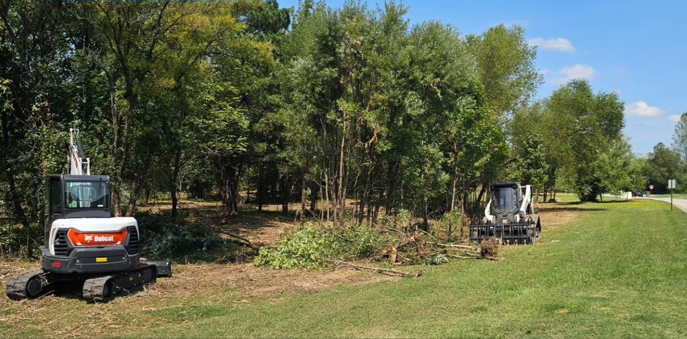 Excavator and skid steer opening a treeline