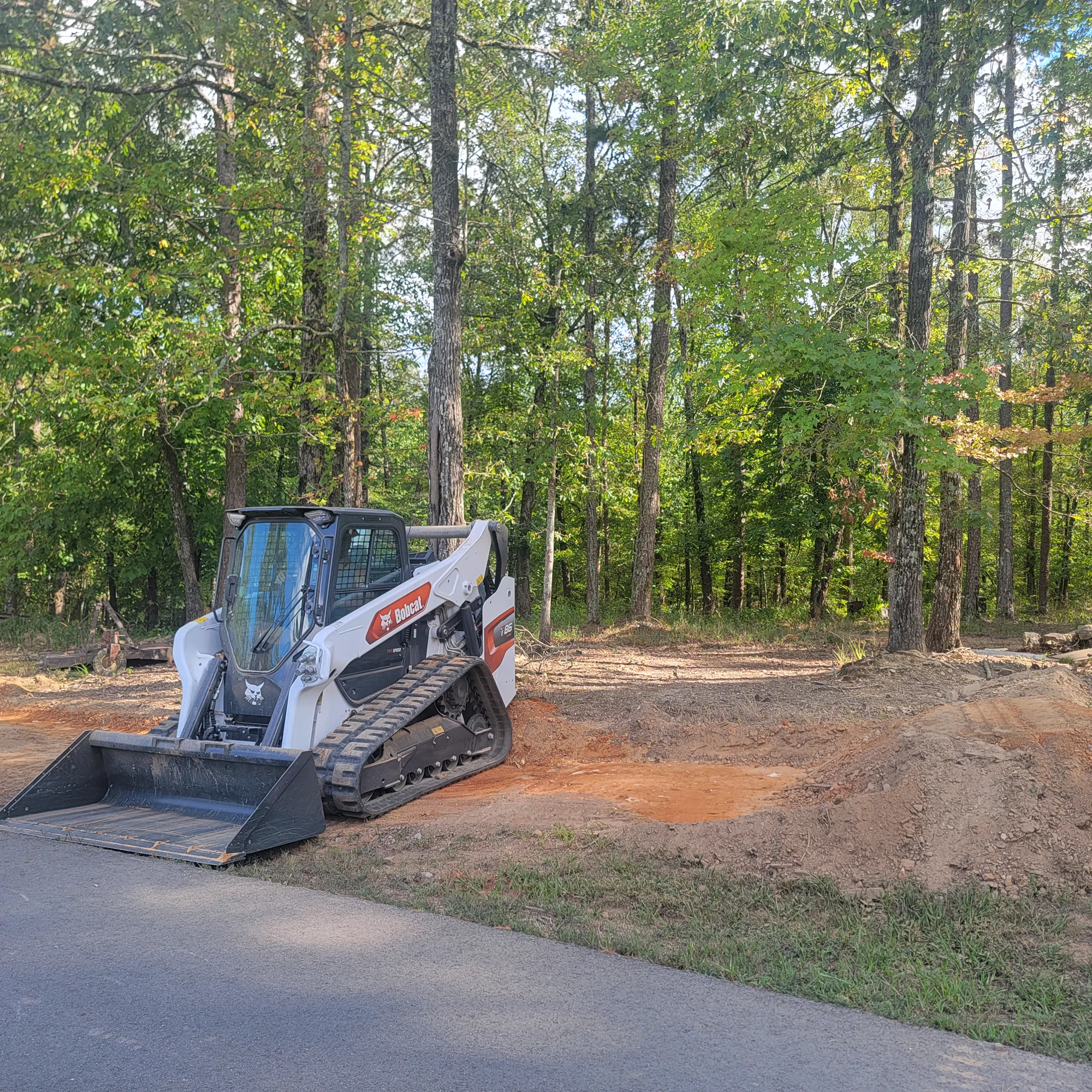 Kingdom Land Services compact equipment at a wooded job site
