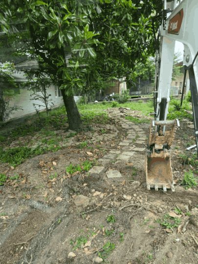 Excavator clearing a backyard during residential demolition